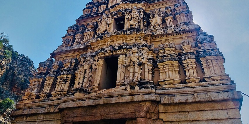 An ancient stone temple with carved pillars, under a clear sky.