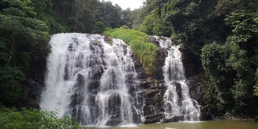 A tiered waterfall flowing into a pool, surrounded by greenery at picnic places in Karnataka.