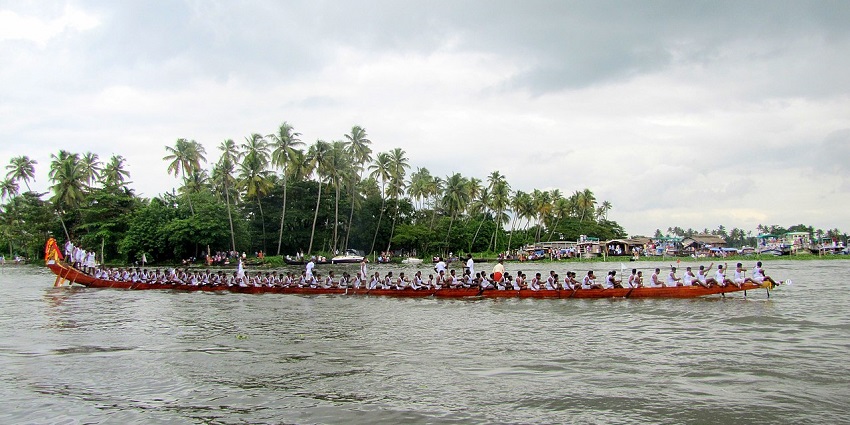 People sitting in a line rowing a snake boat during a boat race at the harvest festival of Kerala in Alappuzha.
