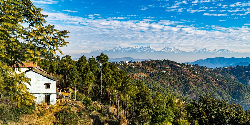 A wide view of a grand fort situated atop a hill with a calm lake in the foreground.
