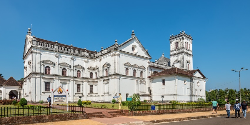 View of the Archaeological Museum of Goa with palm trees and a blue sky above.