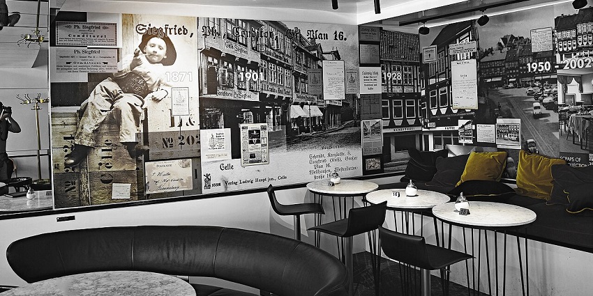Art-deco café interior with monochrome mural wall, round tables, black seating, and spotlights, one of the best cafes in Kalimpong.
