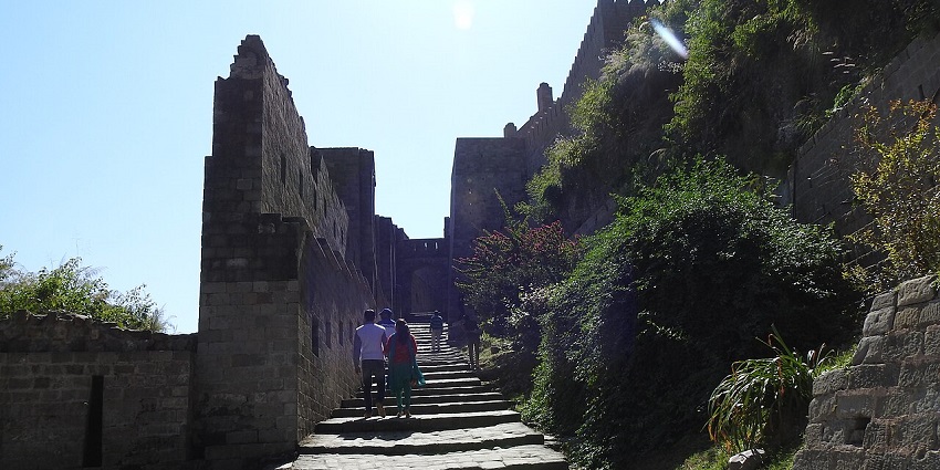 A couple climbs on the stairs of a historical ruin of a fort during the day time.
