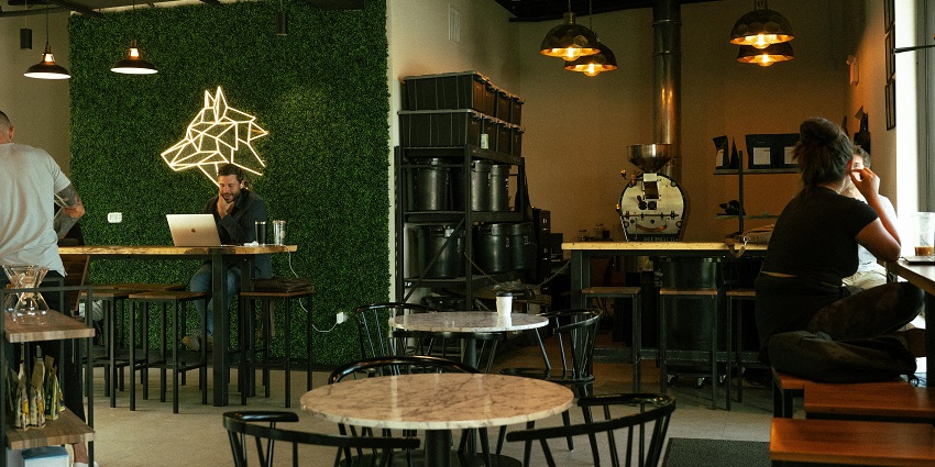 Modern café with neon wolf wall art, marble tables, warm lights and people at work in one of the cafes in Gangtok.
