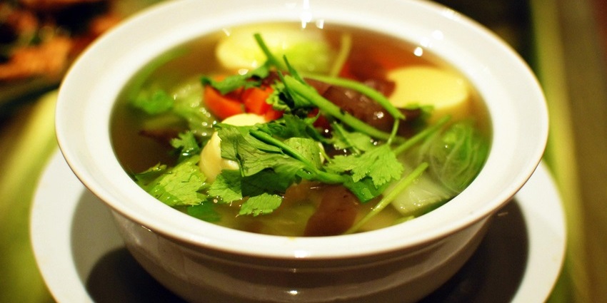 Clear broth soup with soft tofu, vegetables, and herbs, offering a light and comforting meal.