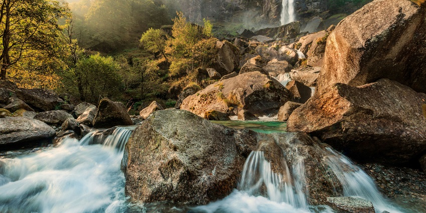 A waterfall cascades down a rocky cliffside surrounded by lush forest.