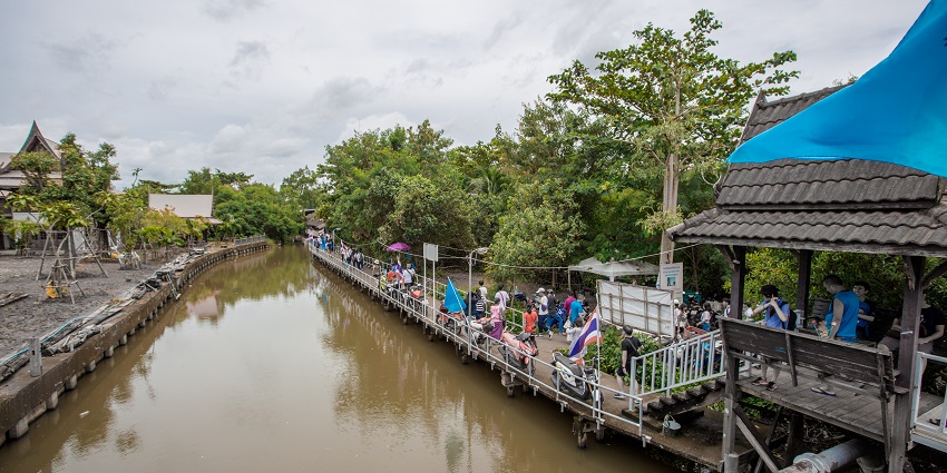 Peaceful view of Bang Nam Phueng Floating Market with boats and riverside stalls.
