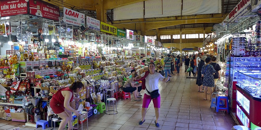 A nighttime view of Ben Thanh Market bustling with shoppers, a hub for shopping in Vietnam.
