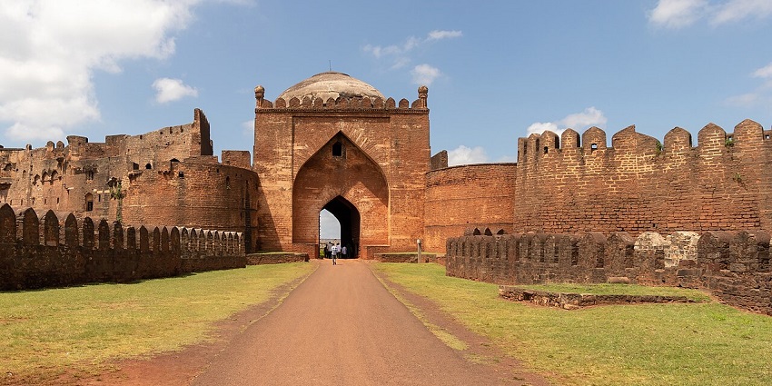 Gumbaz Darwaza of Bidar Fort with an arched gateway and a domed structure under a blue sky.