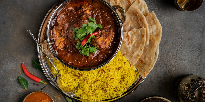 Indian curry served with rice and naan on a restaurant plate.
