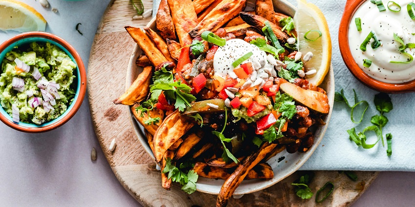 Bowl of sweet potato fries topped with salsa, sour cream, and herbs with dips on side among the multiple restaurants in Havelock Island.
