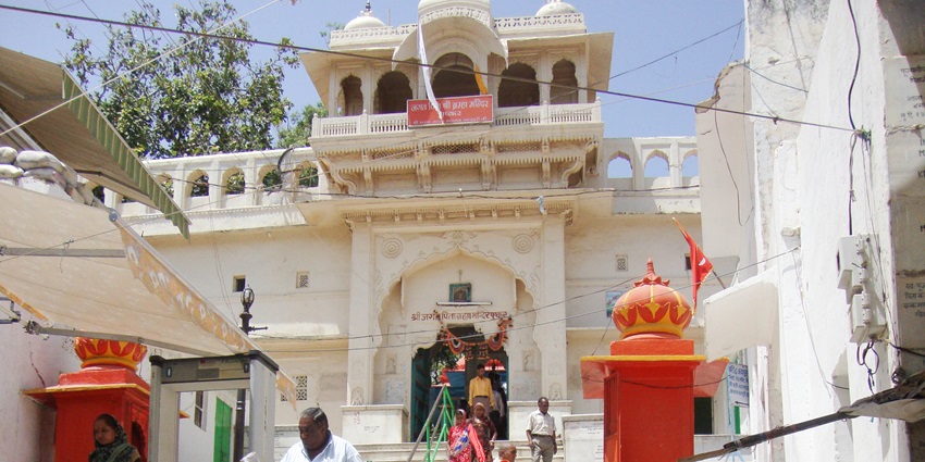 People coming out of the Brahma temple in Pushkar with its white architectural building partially visible.