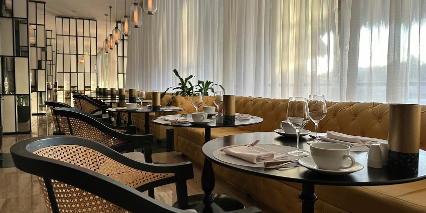 Cosy modern restaurant featuring soft curtains, cushioned booths, and arranged tableware, one of the best restaurants in Clarke Quay.
