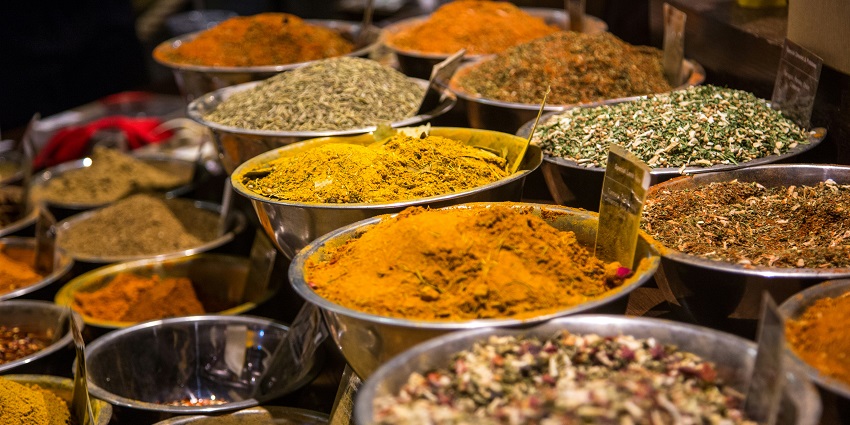 A variety of colorful spices are displayed in open sacks at a street market in Broadway.
