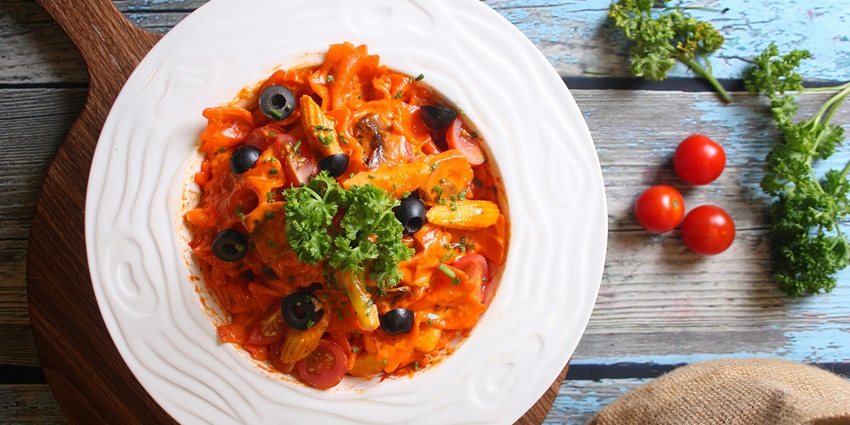 A plate of perfectly cooked penne pasta with a rich red sauce and fresh parsley on top.
