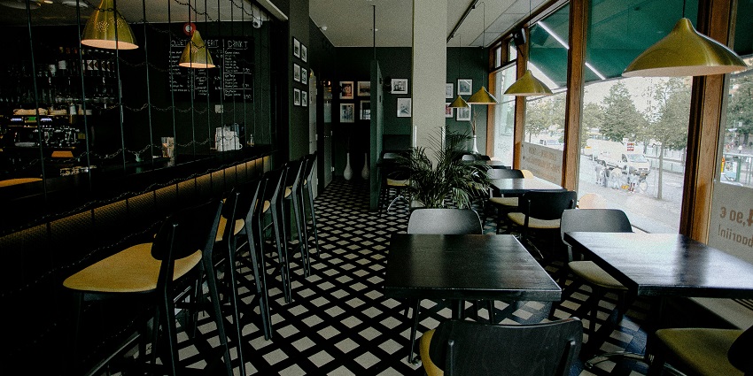 Interior of Cafe Infinity with black tables, chairs, and hanging lights creating a cosy ambience.

