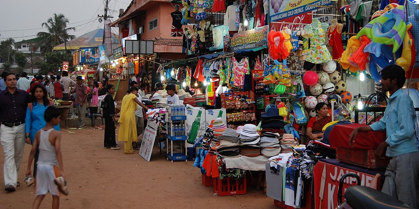 A vibrant street market with many vendors selling clothing, toys, and other goods.