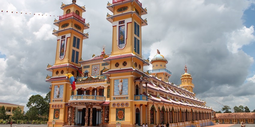 Cao Dai Temple in Tay Ninh with a yellow façade, colorful details, and twin towers, one of the top temples in Vietnam.