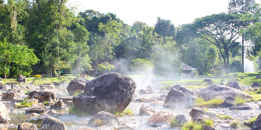 Misty morning at Chae Son Hot Springs in Thailand with steam rising from the water.