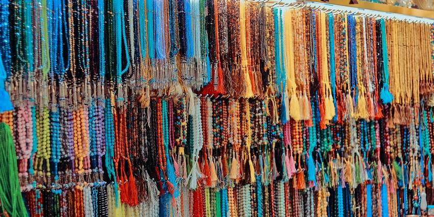 Colourful necklaces hanging on a rack at Chalai Market, a vibrant spot for shopping in Kerala.
