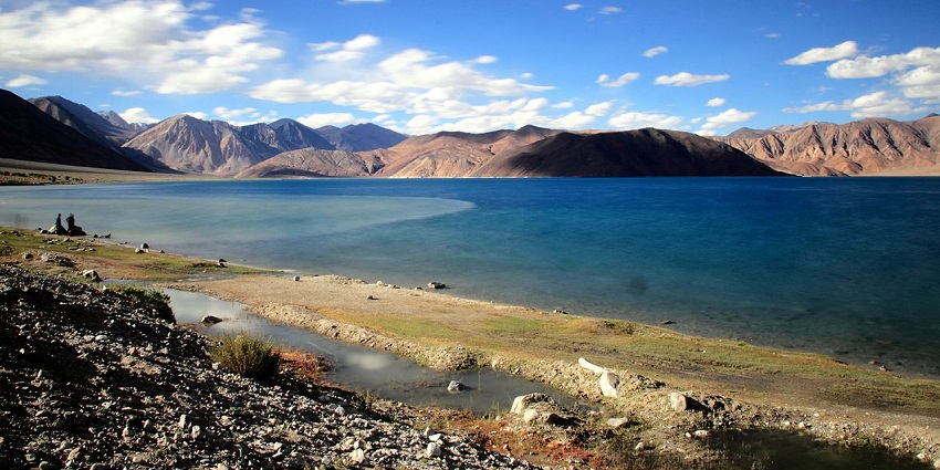 A stunning wide view of a turquoise lake surrounded by a brown mountain range at Chang Chenmo Wildlife Sanctuary.
