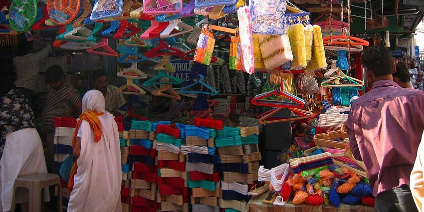 A crowded market stall overflowing with colourful plastic hangers and other items.