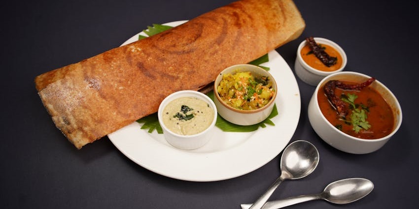 Veg South Indian thali with sambhar, dosa, chutney, and sides served on a plate.