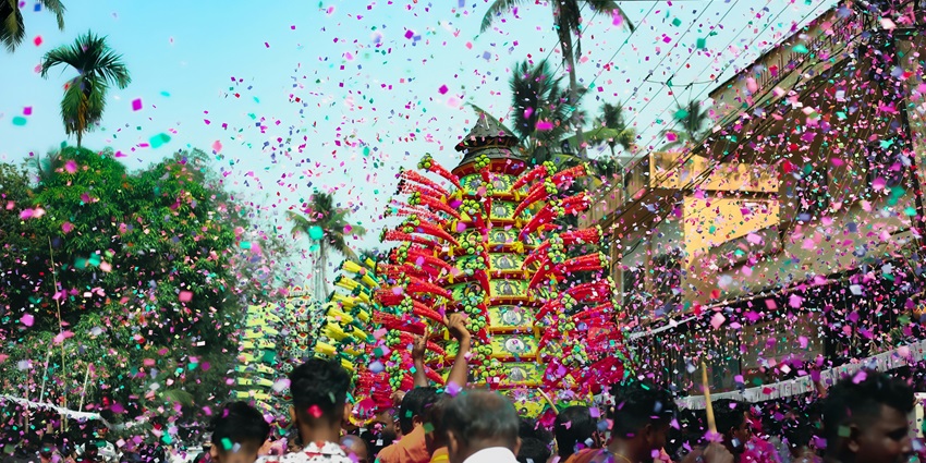 A group of people is celebrating on a street, surrounded by colorful confetti in the air during the Chikal Kalo Festival.