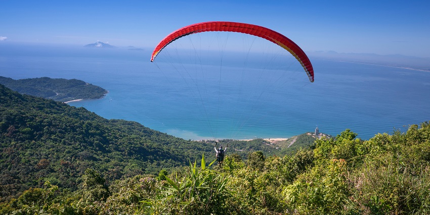 Paragliding over lush green forests in Chikmagalur with clear skies and scenic views.