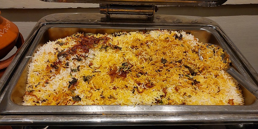 A steaming pot of homemade Hyderbadi Briyani, with rice grains and whole boiled eggs in one of the best restaurants in Siliguri for couples.
