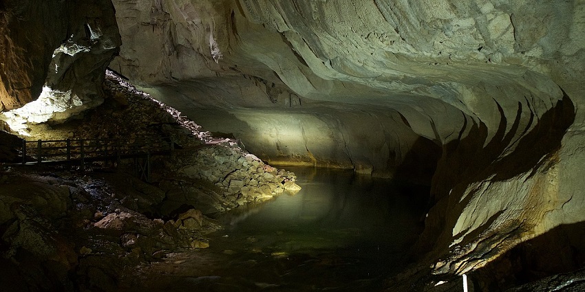 Illuminated interior of Clearwater Cave in Sarawak, showing rock walls and underground river, one of the best caves in Malaysia.
