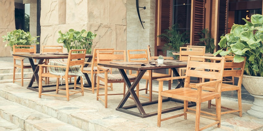 Two sets of brown wooden tables and chairs outside the coffee house, one of the famous cafes in Siliguri.
