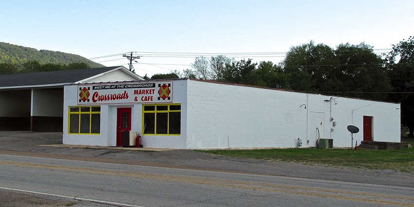 Crossroads Market & Café in a plain white building with red doors and yellow-trimmed windows.