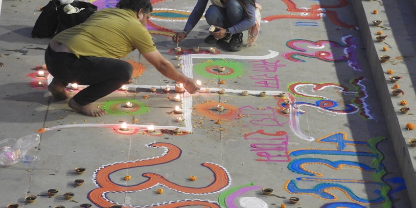 People make a swastika rangoli during the preparation of Dev Deepawali at a ghat in Varanasi.