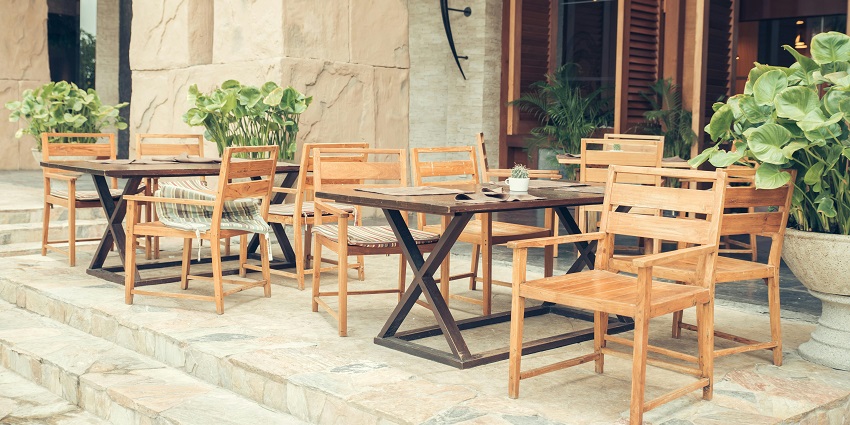 Wooden tables and chairs on a stone patio at an outdoor restaurant seating area, Indian restaurants in Clarke Quay Singapore.
