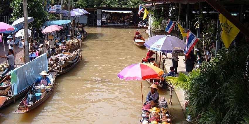 A crowded scene at one of the floating markets in Thailand with boats and vendors.
