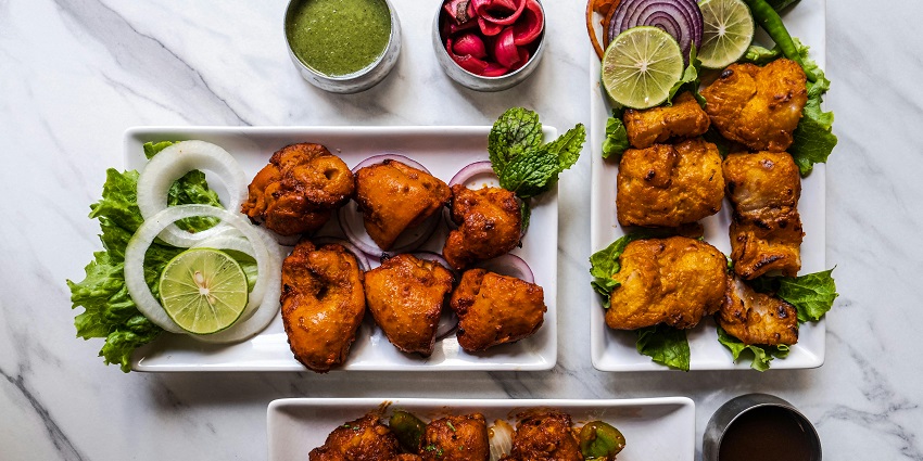 Chicken kebab and tandoori chicken served on a platter at a restaurant table.
