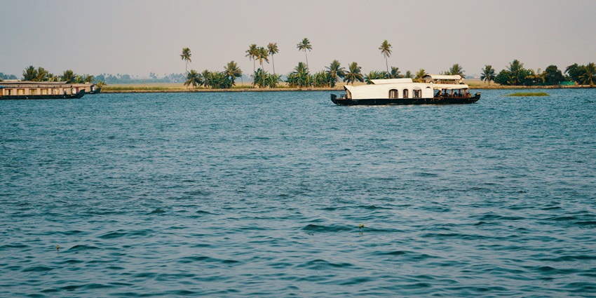 Sandy shoreline with unique rock formations and green trees, one of the stunning islands in Karnataka.