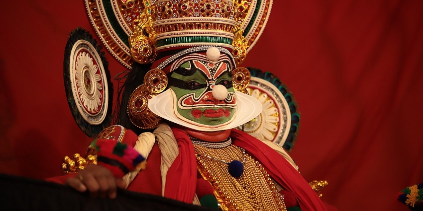 A person dressed in cultural attire performs the Kathakali Dance.
