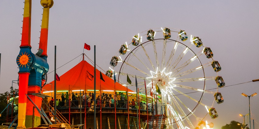 Vibrant fairground during Dussehra celebration in India with rides, lights, and crowds.