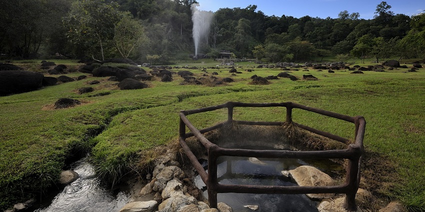 Fang Hot Spring geyser shoots up with steaming pools and green hills, one of the best hot springs in Thailand.