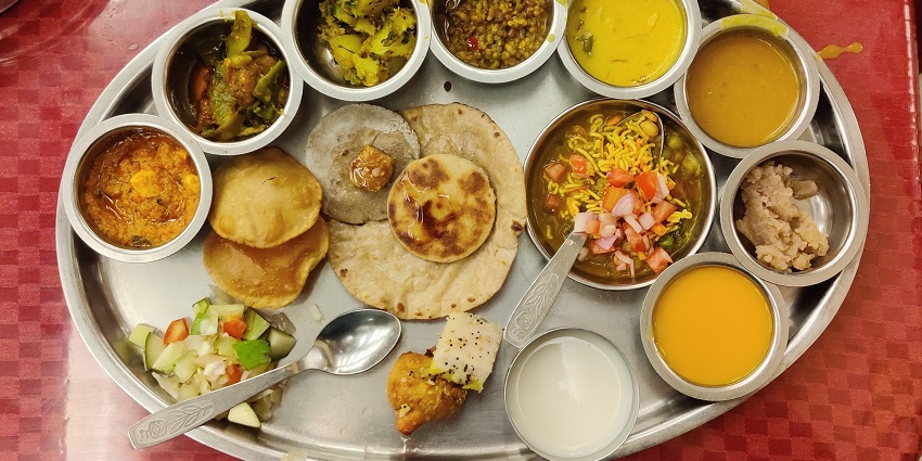 Traditional Gujarati thali with assorted curries, breads, rice, and sweets served on a platter during Rann Utsav.