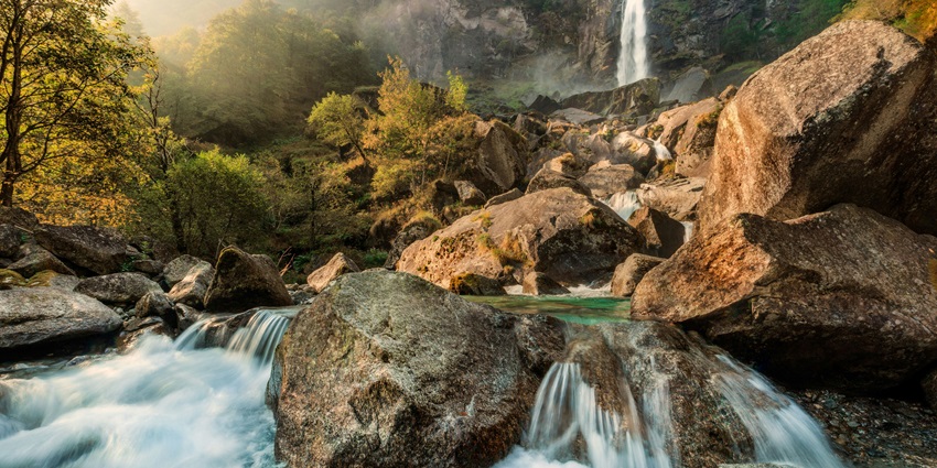 Garwaji Waterfall cascades down rocky cliffs into a serene pool surrounded by trees.