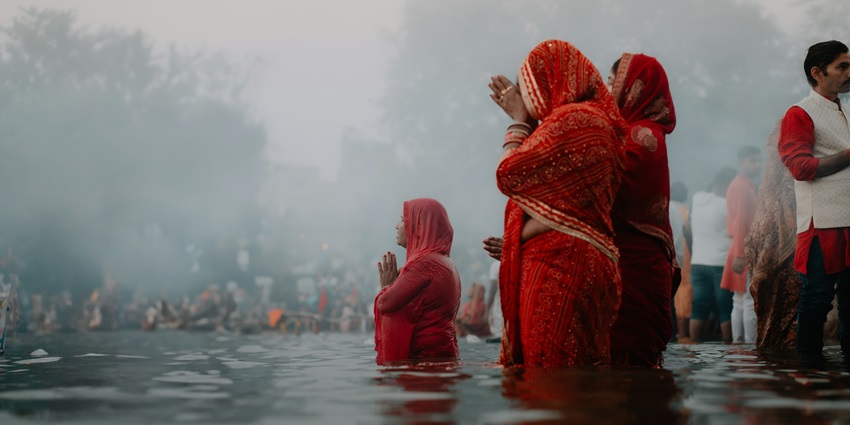 Women performing traditional Chhath Puja rituals at a riverside in Bihar.