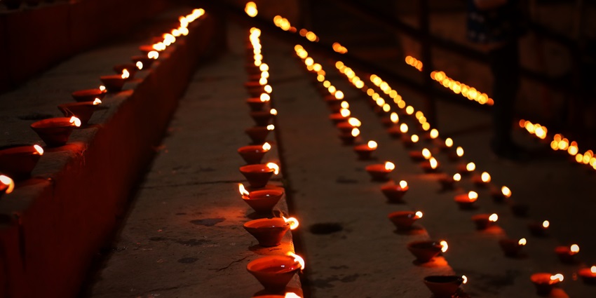 Rows of diyas illuminate a ghat as people take pictures in Varanasi during Dev Deepawali.