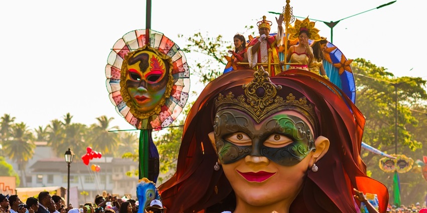 People wearing unique costumes in a vibrant procession during festivals in Goa.