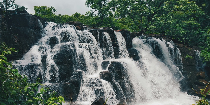 Gokak Waterfalls in the forest cascading over rocky cliffs, surrounded by lush greenery.
