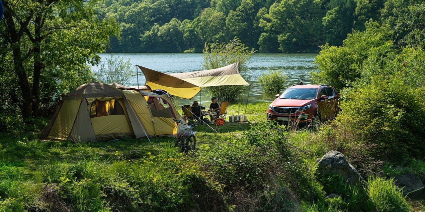Camping tents set up near the calm waters at Gokarna Beach surrounded by sand.