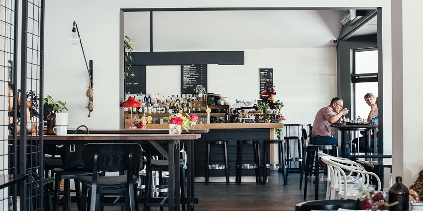 Minimalist coffee counter with stacked cups, glass jars, greenery and rustic decor
