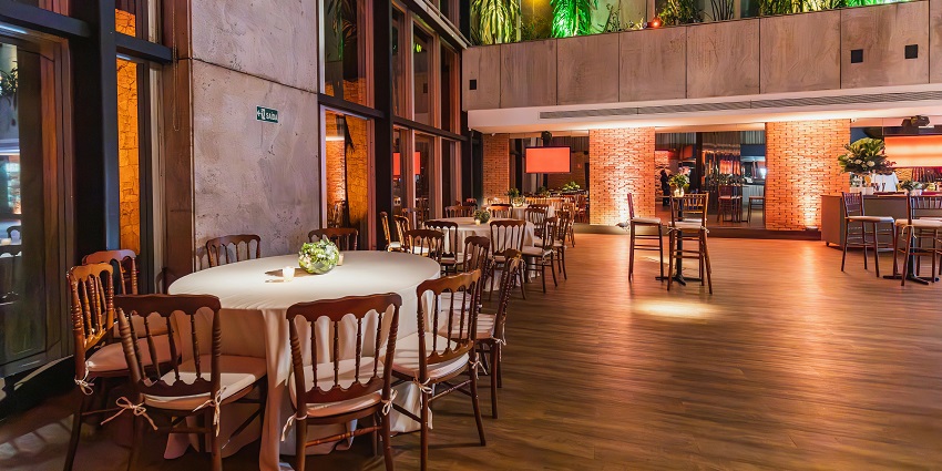 Elegant hall with round tables, wooden chairs and warm evening lighting, one of the restaurants in Kurseong.